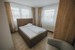 a bedroom with a bed and a chair and windows at Endlich zuhause in Sibiu +32 photos