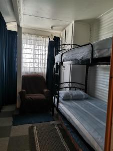 a bedroom with two bunk beds and a chair at Kayser's Sea Breeze in East London