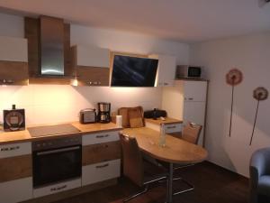 una cocina con mesa de madera y una pequeña cocina con mesa y barra. en Ferienhaus am Wald, en Loissin