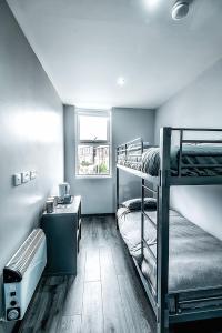 a dorm room with two bunk beds and a desk at The Anfield Rooms in Liverpool