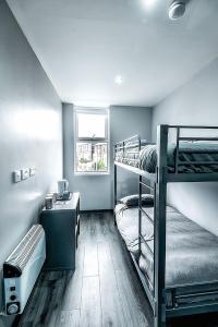 Schlafsaal mit 2 Etagenbetten und einem Schreibtisch in der Unterkunft The Anfield Rooms in Liverpool
