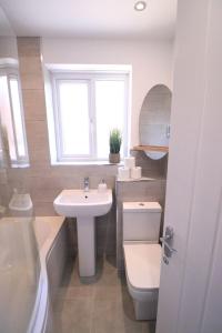 ein Bad mit einem Waschbecken, einem WC und einem Fenster in der Unterkunft Amaya Three - Newly Renovated - Sleeps 6 - Grantham in Grantham