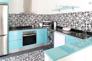 eine Küche mit blauen Schränken und einer schwarz-weißen Tapete in der Unterkunft Aqua Apartments Málaga in Málaga