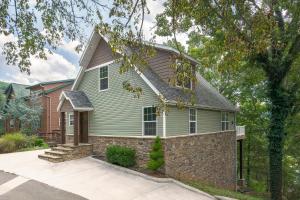 a green house with a stone wall at Mountain Creek Cabin - Luxury Lakefront Home - Hot Tub- Pool Table - Movie Theater in Lampe
