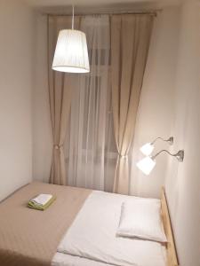 1 dormitorio con 1 cama con lámpara y cortina en Apartamenty Winnicy Kresy II, en Cracovia