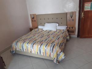 a bedroom with a bed with a striped comforter at HOTEL VELLEDA in Rabat