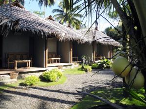ein Haus mit Strohdach und Innenhof in der Unterkunft Bale Karang Cottages in Batukaras