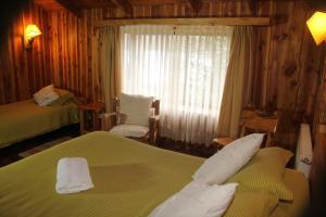 Habitación de hotel con 2 camas y ventana en Hosteria-Cabañas Rucapillan en Choshuenco