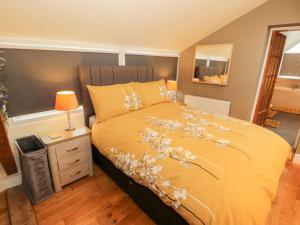 a bedroom with a yellow bed with flowers on it at Rhiw Afallen in Caernarfon
