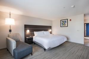 a hotel room with a bed and a chair at Holiday Inn Express & Suites Chicago - Hoffman Estates, an IHG Hotel in Hoffman Estates