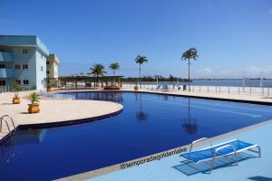 a large blue swimming pool next to a beach at Temporada Golden Lake in Arraial do Cabo