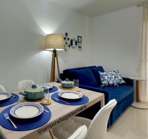 a living room with a table and a blue couch at Temporada Golden Lake in Arraial do Cabo