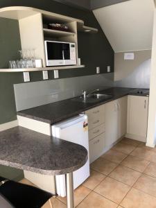 a kitchen with a counter and a sink and a microwave at Wylie Court Motor Lodge in Rotorua