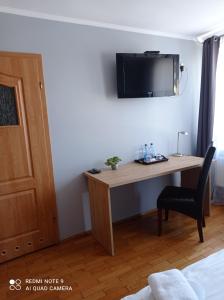 Habitación con escritorio y TV en la pared. en Stary Młyn en Żory