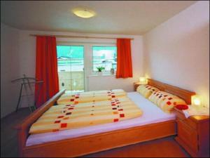 a bedroom with two beds and a window with red curtains at Anton´s Appartements in Oetz