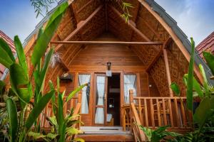 Cette cabane en rondins dispose d'une grande porte en bois et d'une terrasse couverte. dans l'établissement Penida Krusty Hill by ecommerceloka, à Nusa Penida