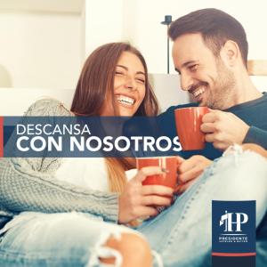 a man and a woman sitting on a couch holding coffee cups at Hotel Presidente in Santiago