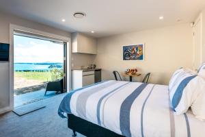 1 dormitorio con 1 cama y puerta corredera de cristal en The Apartment - Sea Views at Te Whau Point by Waiheke Unlimited en Omiha