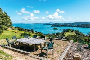 einen Tisch mit Stühlen und Seeblick in der Unterkunft The Apartment - Sea Views at Te Whau Point by Waiheke Unlimited in Omiha