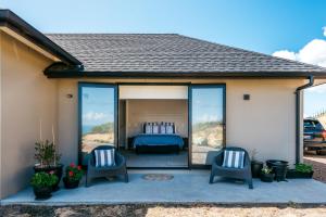 Habitación con patio con 1 cama y 2 sillas. en The Apartment - Sea Views at Te Whau Point by Waiheke Unlimited en Omiha
