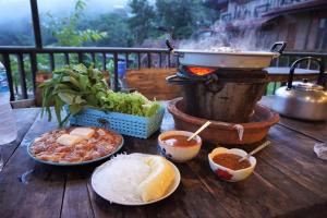 einen Tisch mit Tellern und einem Grill in der Unterkunft Bann Suan Maya in Mae Rim