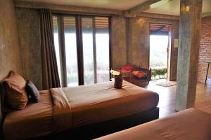 a bedroom with two beds and a large window at Bann Suan Maya in Mae Rim