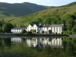 a large white house next to a body of water at Leenane Hotel in Leenaun