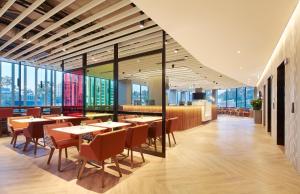 um restaurante com mesas e cadeiras e janelas grandes em Holiday Inn Express Sydney Airport, an IHG Hotel em Sydney