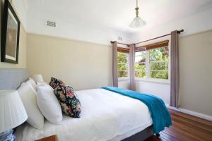 Un dormitorio con una cama blanca y una ventana. en Rodova Cottage, en Katoomba