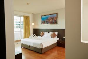 ein Schlafzimmer mit einem großen Bett und einem Gemälde an der Wand in der Unterkunft Rhienchai Place Hotel in Surat Thani