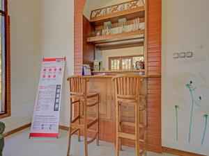 a kitchen with a bar with two stools and a sign at Super OYO 3208 Villa Inn App Trawas Bintaro Syariah in Kemloko-gede