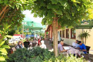 un grupo de personas sentadas en mesas bajo un árbol en Hotel-Landgasthaus Ständenhof en Ruppertsweiler