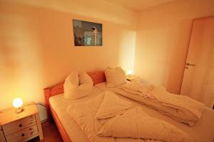 una camera da letto con letto, lenzuola e cuscini bianchi di Ferienpark N09-008 Ferienpark a Heiligenhafen