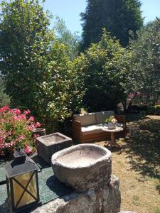 a garden with a bench and a table and trees at Casa da Posta de Valmaior in Boiro