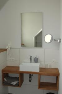 ein Badezimmer mit einem weißen Waschbecken und einem Spiegel in der Unterkunft Ferienwohnung Lodberger Scheunencafe in Löningen