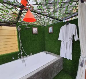 La salle de bains est pourvue d'une baignoire et de murs verts. dans l'établissement Baansuan Chomchun, à Amphoe Mae Taeng
