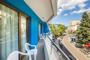 a balcony with two white chairs and a blue wall at Kuban Resort & Aquapark - All Inclusive in Sunny Beach