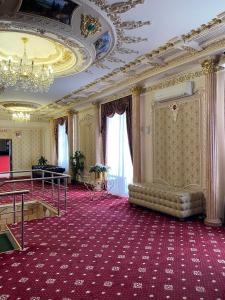 Großes Zimmer mit einem Kronleuchter und einem roten Teppich. in der Unterkunft Lion Hotel in Astana