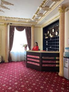 une femme assise à un bureau dans une chambre d'hôtel dans l'établissement Lion Hotel, à Astana