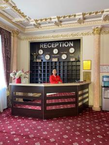 a woman sitting at a reception desk in a room at Lion Hotel in Astana