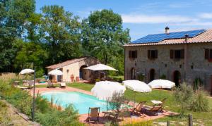 a house with a pool and a building with umbrellas at Podere i Melograni in Guardistallo