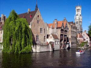 a group of people in a boat on a river with buildings at Logies Graaf Van Vlaanderen in Bruges