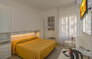 sypialnia z żółtym łóżkiem i biurkiem w obiekcie City Hotel w Viareggio