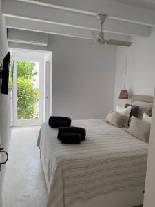 a white bedroom with a large bed with black pillows on it at Es Chalet in Sant Lluis