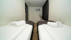 two beds in a room with white sheets and towels at Leidse Square City Centre Private Apartments in Amsterdam