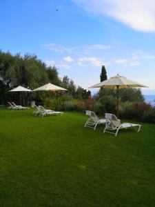 a group of chairs and umbrellas on a lawn at Nikoli Apartments in Benitses