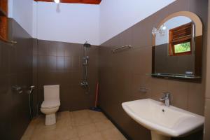 La salle de bains est pourvue d'un lavabo, de toilettes et d'un miroir. dans l'établissement Freedom Guest Inn Ella, à Ella