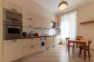 une cuisine avec des placards blancs et une table avec des chaises dans l'établissement Rione Prati Apartment - MM Lepanto, à Rome