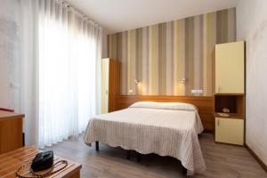 um quarto com uma cama e uma televisão em Hotel Rosa em Lido di Jesolo