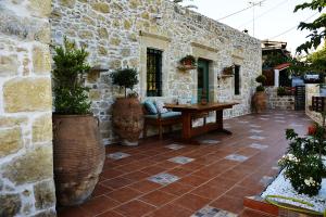 een patio met een houten tafel en een stenen muur bij Joakim's Villa in Pitsidia